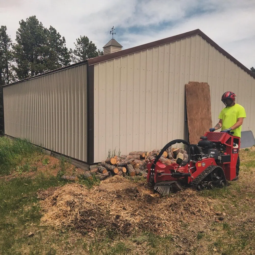 Canyon Falls Tree Works stump grinding equipment removing a stump next to a fence in Rapid City SD